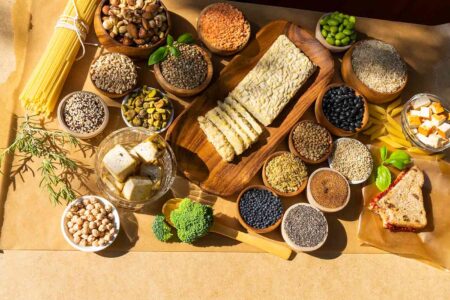 a table with more than a dozen samples of vegan protein from pasta to chia seeds broccoli beans and more