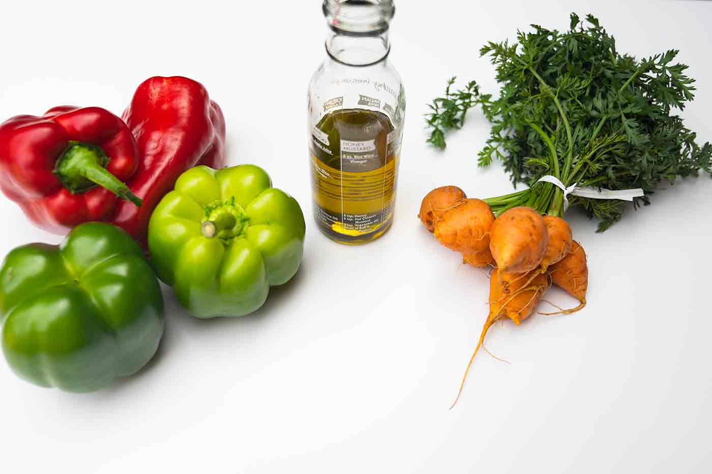 fresh peppers and carrots with a flask of olive oil