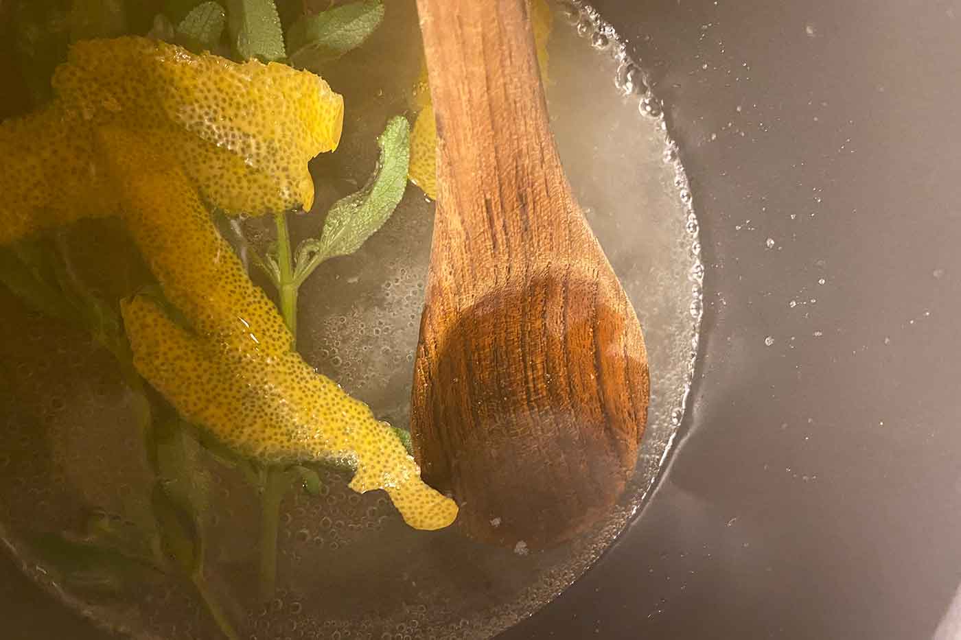 simple syrup cooking on the stove with lemon peel and sage to add to a cocktail recipe