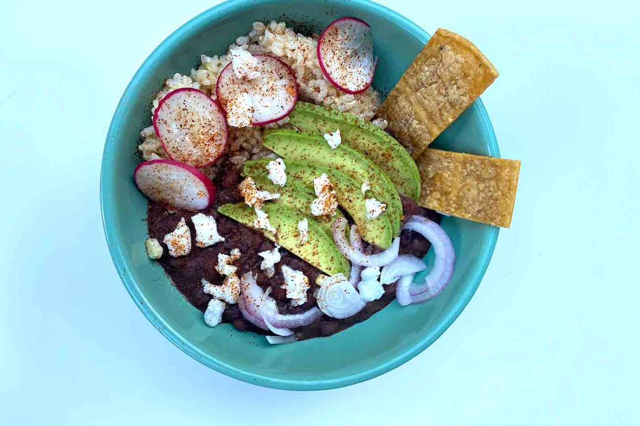 vegan burrito bowl with red onion avocado vegan Cotijo cheese radishes chips beans and brown rice