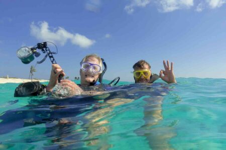 two scuba divers with cameras ready to descend Bonaire Island