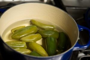 pot of cooked jalapeno peppers on the stove in a blue le creuset pan