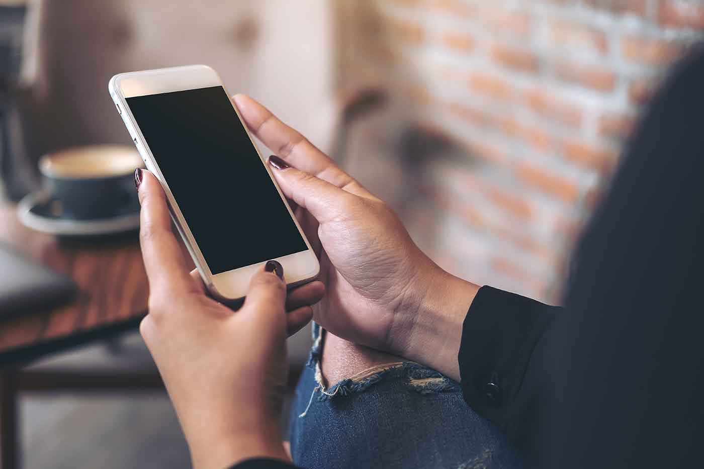 woman at a cafe holding her phone